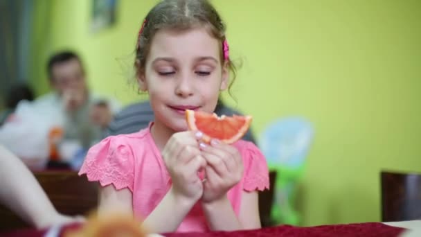 Kleines Mädchen probiert Scheibe Grapefruit — Stockvideo