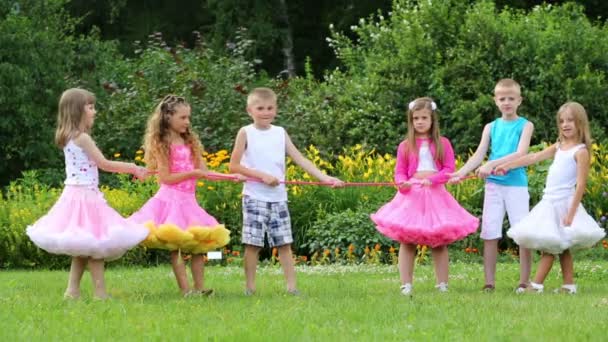 Kinder ziehen Seil in der Nähe von Blumenbeeten — Stockvideo