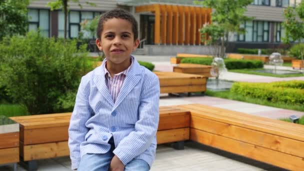 Niño feliz con chaqueta se sienta — Vídeo de stock