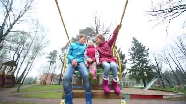 Menino e duas meninas em balanços — Vídeo de Stock