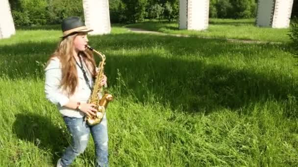 Девушка в шляпе играет на саксофоне — стоковое видео