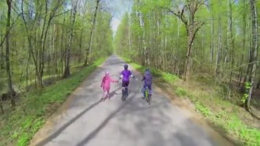 Üç kişi rollerskates ve bisiklet sürmek