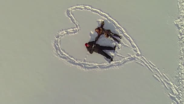 Casal deitado na neve dentro do coração . — Vídeo de Stock