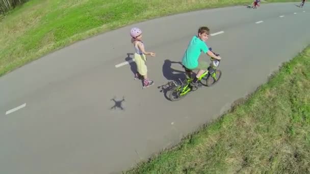 Zwei Kinder fahren auf Rollschuhen und Fahrrad — Stockvideo