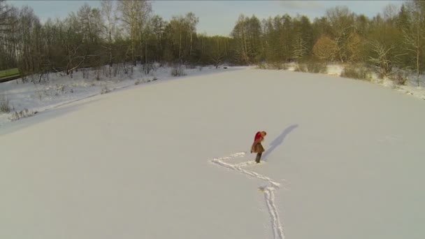 Woman leaves trail on snowbound pond — Stock Video
