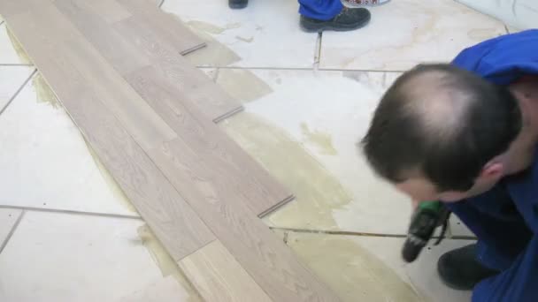 Zwei Arbeiter verlegen Bodenbelag — Stockvideo