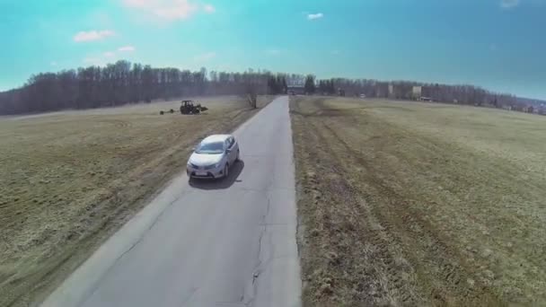 Автомобиль начинает ездить по дороге рядом с полями — стоковое видео