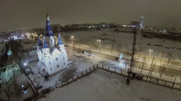 Автомобили едут по дороге возле освещенной церкви — стоковое видео