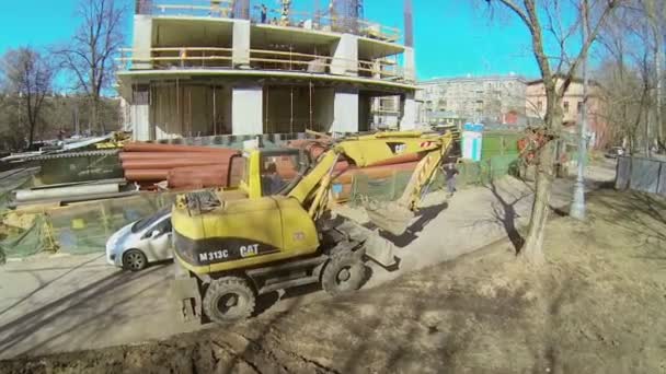 Excavator rides near building site — Stock Video