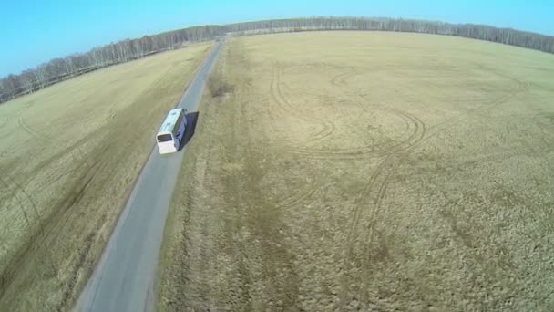 Buss rider på väg bland fält — Stockvideo