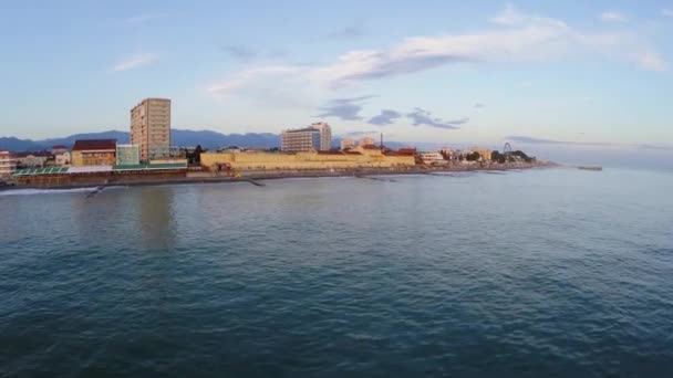 Ciudad costera cerca de las montañas durante el atardecer — Vídeo de stock