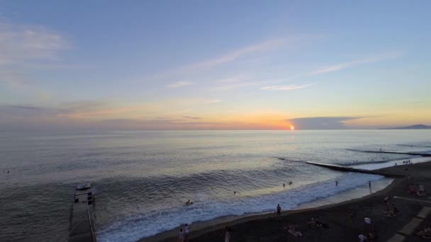 Pessoas na praia do mar durante o pôr do sol — Vídeo de Stock