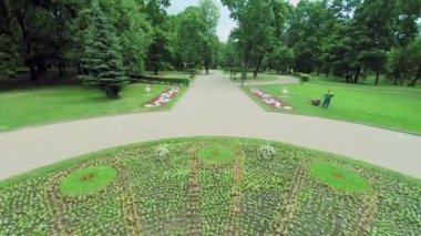 Worker stands on grassplot near flowerbed in park