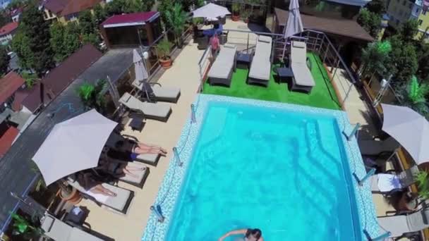 Menschen auf Sonnenliegen und im Pool — Stockvideo