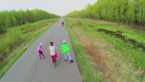 People ride on rollerblades and bicycle — Stock Video