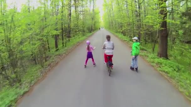 People ride on rollerblades and bicycle — Stock Video