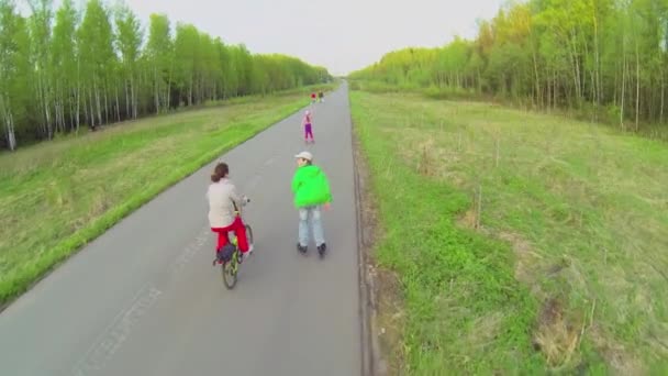 Menschen fahren auf Inlinern und Fahrrädern — Stockvideo