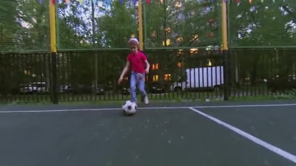 Kleines Mädchen führt Fußballball am Frühlingsabend durch Spielplatz — Stockvideo