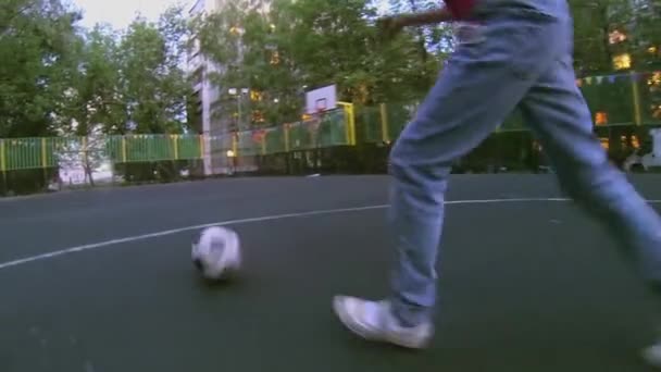 Meisje leidt bal tot voetbal poort op speelplaats op lente avond — Stockvideo