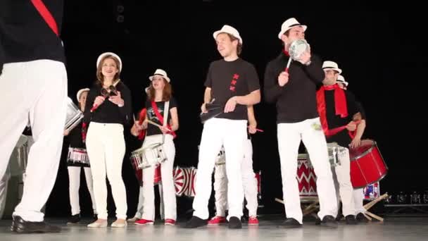 Doze pessoas em chapéus tocam bateria na sala de concertos no palco — Vídeo de Stock