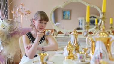 Beyaz güzel kız masada oturur, içecekler ve çay döker