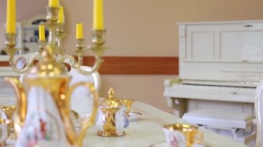 Güzel kız mumlar ve porselen ile masada oturur