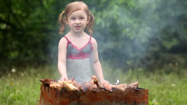 Mała dziewczynka sprawia, że grill grilla na zielony trawnik. — Wideo stockowe