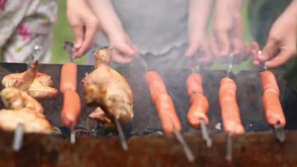 Τα χέρια των παιδιών περιστρέφονται σουβλάκια με κοτόπουλα και λουκάνικα. — Αρχείο Βίντεο
