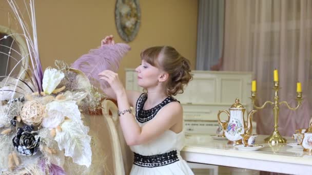 Belle fille s'assoit à table et essaie grande plume — Video