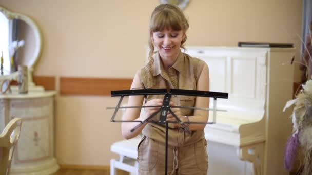 Beautiful girl installs music stand in room with classic interior — Stock Video
