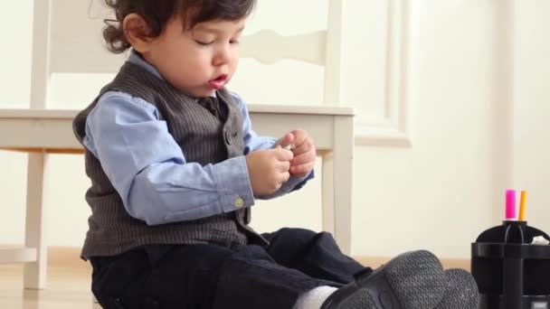 Cute baby boy in suit sits on floor near white chair — Stock Video