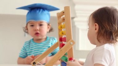Mavi mezuniyet şapka iki sevimli bebekler masada abacus ile oynamak