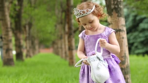 Güzel mor elbise ve taç küçük kız çanta tutar — Stok video