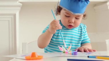 Mavi mezuniyet şapka iki sevimli erkek bebek masada renkleri boyar