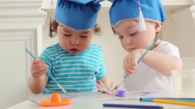 Mezuniyet şapkaları iki bebek erkek ve kız masaya renkleri boya