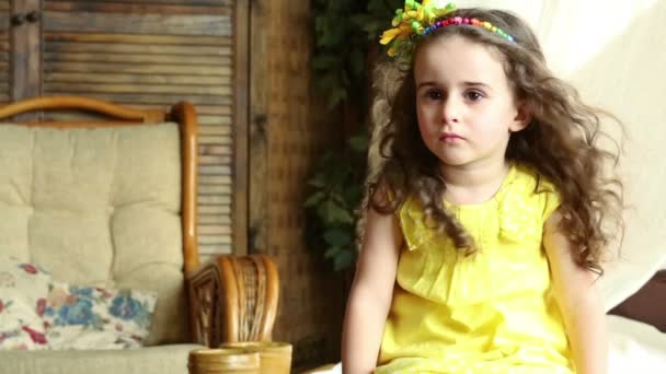 Маленькая девочка сидит перед вентилятором и смотрит в камеру . — стоковое видео