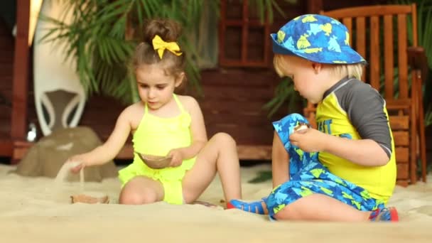 Küçük bir çocuk ve kumla oynayan kız — Stok video