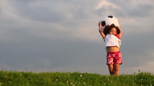 Liten söt flicka kastar uppblåsbara fotboll ballongen grön äng — Stockvideo
