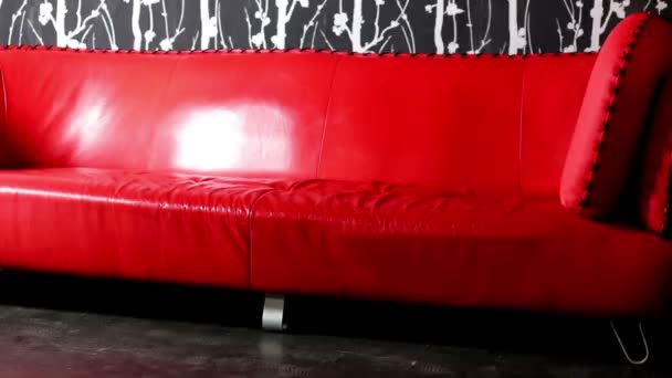 Gran sofá rojo que se encuentra cerca de la pared con colgante negro . — Vídeo de stock