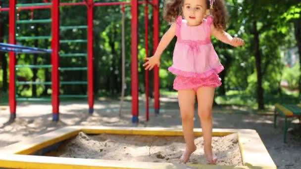 Meisje springen op sandbox. — Stockvideo
