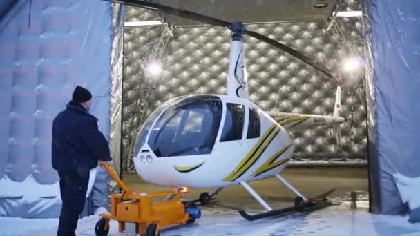 Adam beyaz helikopter bir hangarda koyar. — Stok video