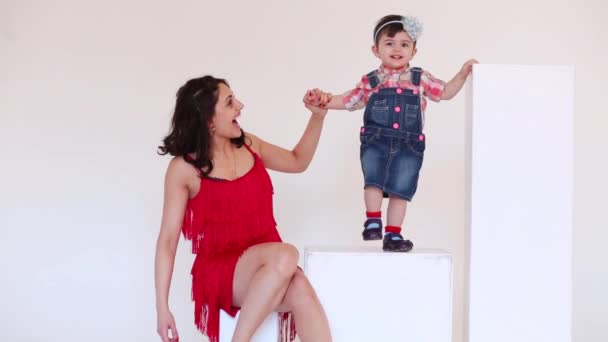 Chica sonriente en vestido rojo sosteniendo la mano de su hija — Vídeo de stock