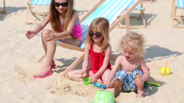Tres niños juegan en la arena — Vídeo de stock