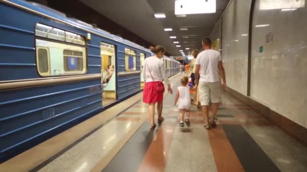 Семья в метро рядом с синим поездом — стоковое видео
