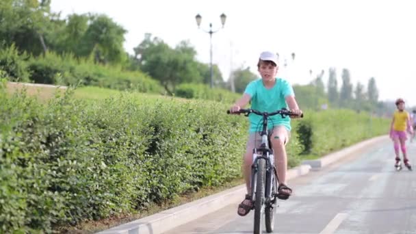 Menino na bicicleta e menina em rolos — Vídeo de Stock