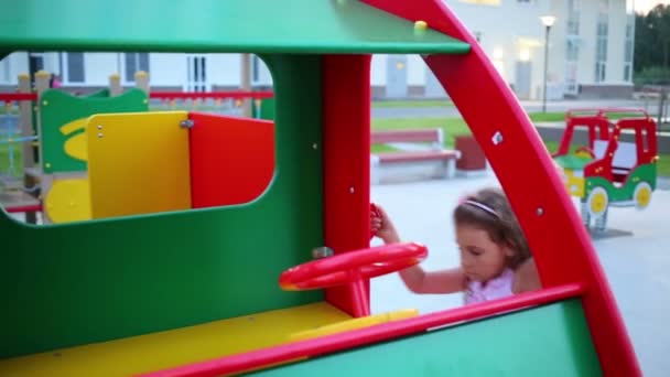 Mädchen sitzt auf Spielzeugauto aus Holz — Stockvideo