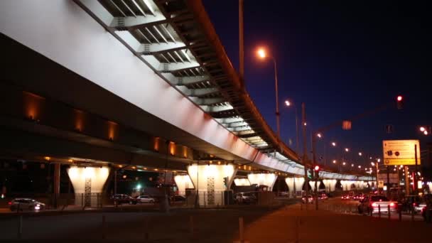 Muchos coches viajan en la carretera cerca de paso elevado en la noche oscura — Vídeos de Stock