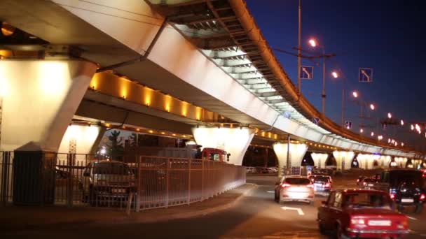 Tył wielu samochodów poruszających się na drodze w pobliżu Overpass w ciemnej nocy — Wideo stockowe