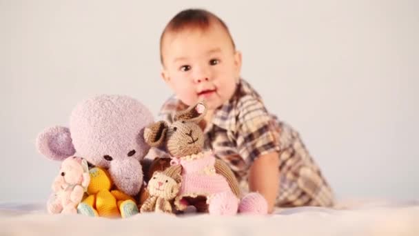 Der kleine Junge krabbelt zum Spielzeughaufen und wirft ihn — Stockvideo