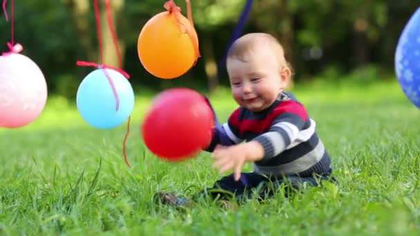 Воздушные шары висят на веревке и ребенок ловит воздушный шар — стоковое видео